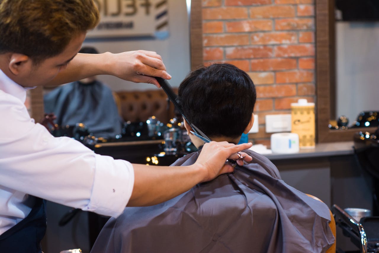 Barber giving a precise haircut to a client in a contemporary barbershop setting.