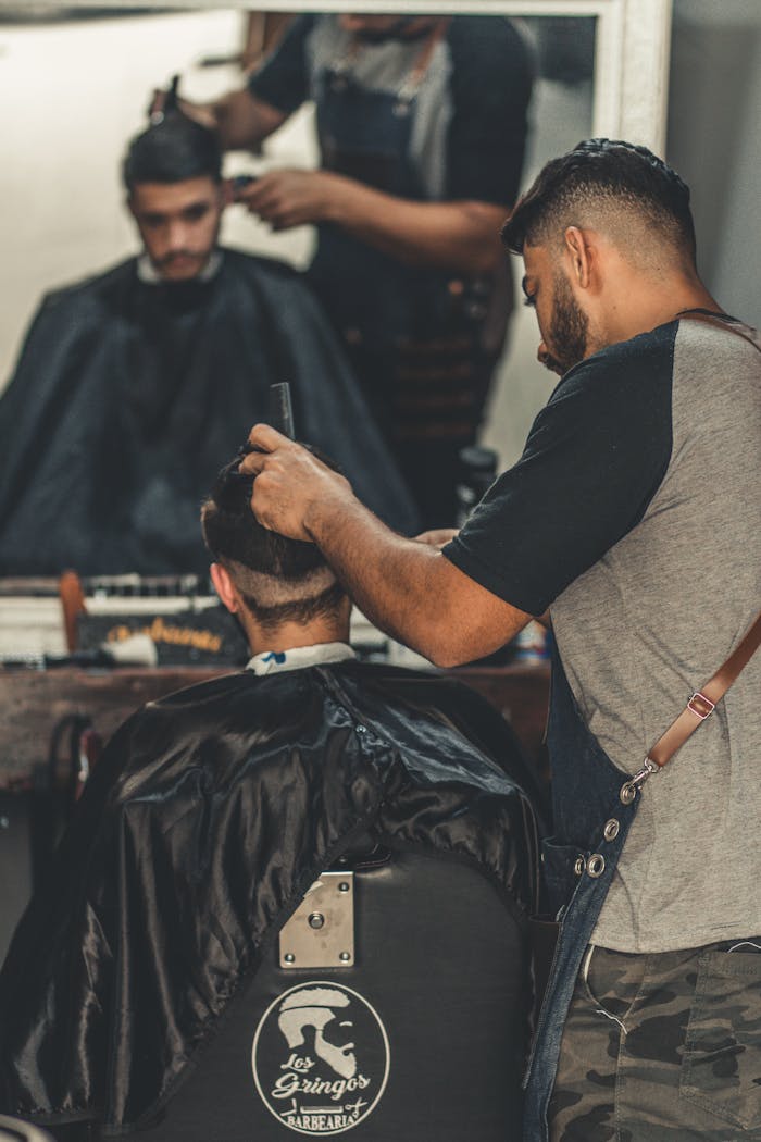 Professional barber crafting a modern hairstyle at a barbershop, reflecting style and grooming culture.