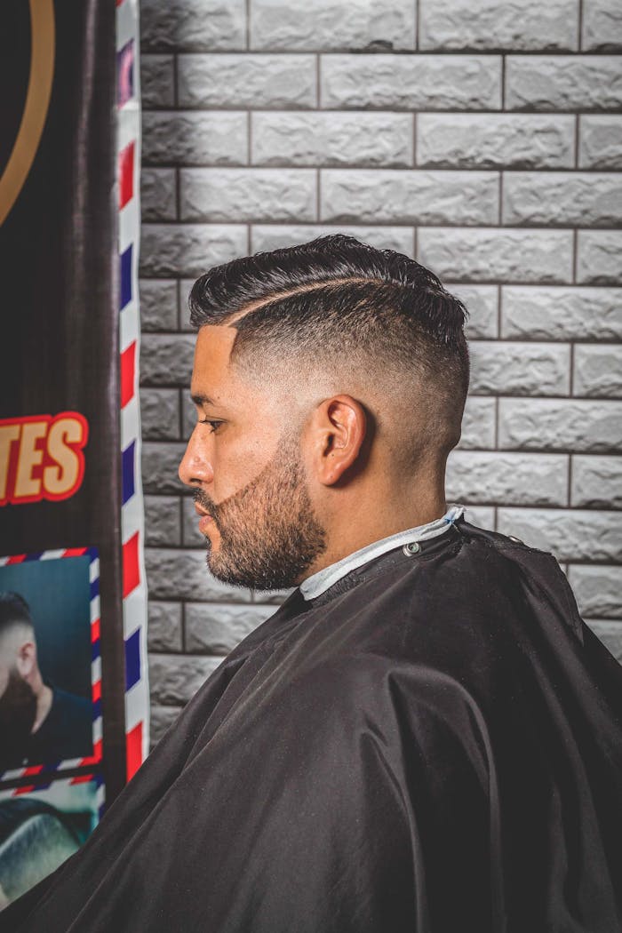 Profile view of a man with a stylish haircut in a barber shop.